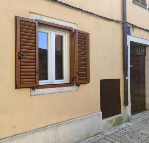 ein Fenster auf der Seite eines Gebäudes mit Fensterläden aus Holz in der Unterkunft Studio Femi in Rovinj