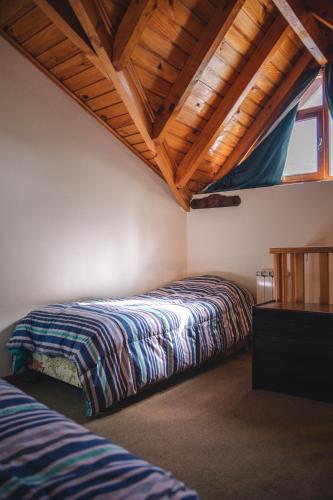 a bedroom with two beds and a wooden ceiling at Hosteria Las Lengas by Visionnaire in San Martín de los Andes