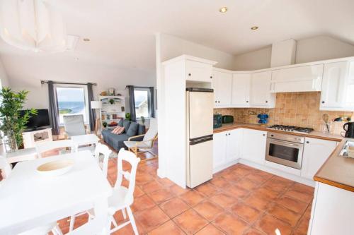 uma cozinha e sala de estar com armários brancos e uma mesa em Fishermans Cottage Stunning Two Bedroom with Views close to town em Bundoran