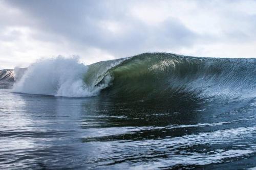 a large wave in the ocean on a cloudy day at Fishermans Cottage Stunning Two Bedroom with Views close to town in Bundoran