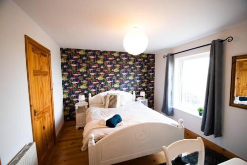 a bedroom with a white bed and a floral wall at Fishermans Cottage Stunning Two Bedroom with Views close to town in Bundoran