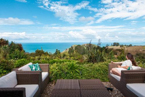 a woman sitting on a couch looking at the ocean at Orokawa Bay Retreat in Waihi