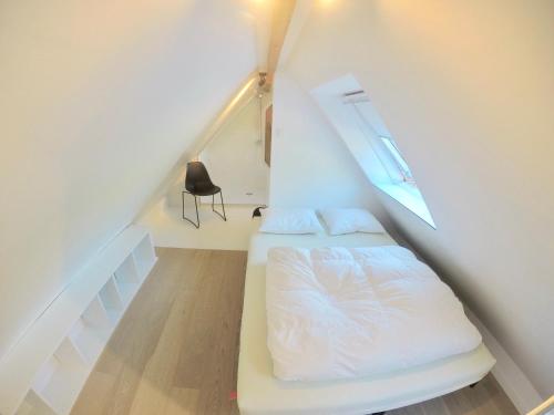 um pequeno quarto com uma cama no sótão em Chaleureux em Wenduine