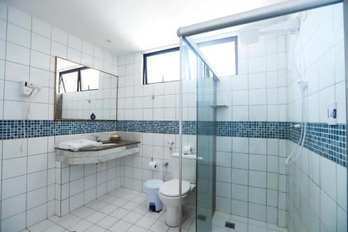 a bathroom with a toilet and a glass shower at Hotel da Costa By Nobile in Aracaju