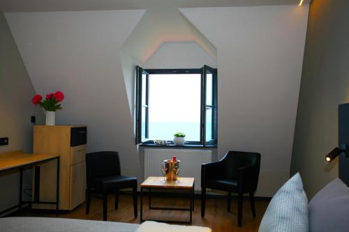 een kamer met stoelen, een tafel en een raam bij Alte Molke Apartment 10 in Meersburg