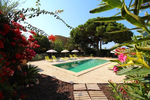 a pool with chairs and umbrellas in a yard at Casa Canavial in Lagos