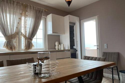 a kitchen with a wooden table with chairs and windows at Cozy Lake Front Flat Bequeme Wohnung an der See in Pogradec