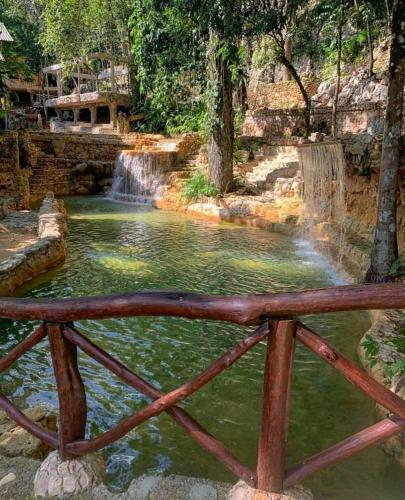 a wooden fence in front of a waterfall at Paraiso Caño Hondo in Los Guineos Perdidos