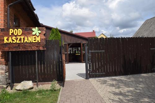 a wooden gate with a sign in front of a building at Pensjonat pod Kasztanem in Ełk