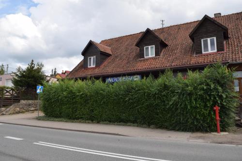 a house on the side of a street with a bush at Pensjonat pod Kasztanem in Ełk