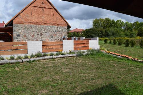 a fence in front of a building with a barn at Pensjonat pod Kasztanem in Ełk
