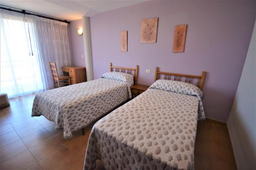 um quarto de hotel com duas camas e uma janela em Apartamentos de playa en un entorno rural em Sanxenxo