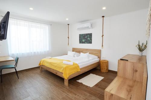 a bedroom with a bed with a yellow blanket and a desk at Naturella Panzió in Villány