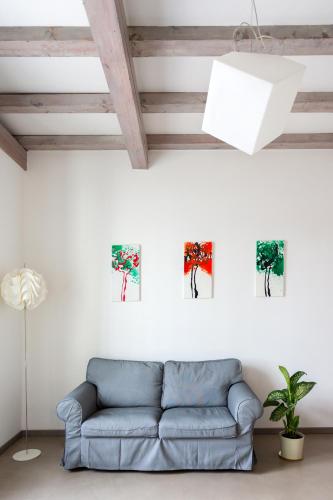 a living room with a blue couch and paintings on the wall at La Maison Des Lions APPARTAMENTI VACANZE accesso diretto alla spiaggia località Amore in Cannobio