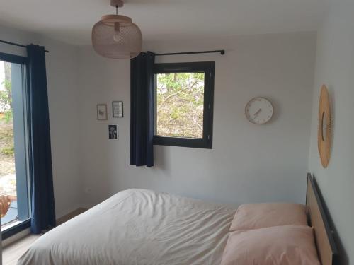 une chambre avec un lit et une horloge au mur dans l'établissement Agréable Villa Domaine du Golf Piscine CHAUFFEE, à Biscarrosse