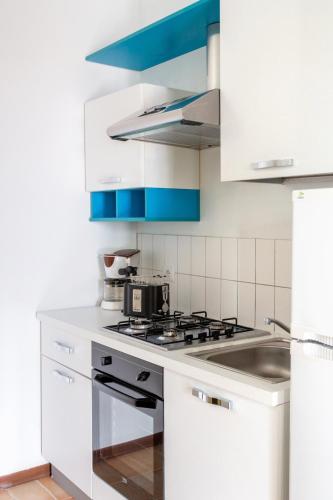 a white kitchen with a stove and a sink at La Maison Des Lions APPARTAMENTI VACANZE accesso diretto alla spiaggia località Amore in Cannobio