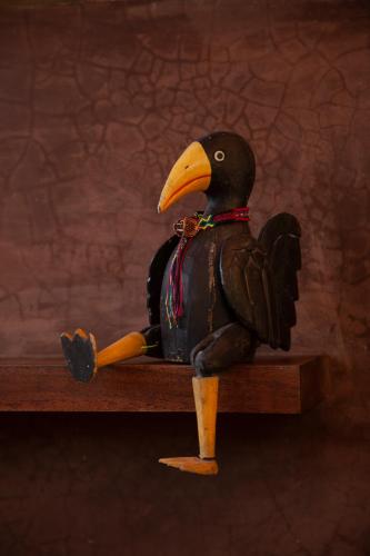 a plastic bird sitting on a wooden table at M a r e a V i v a - O a x a c a in Zipolite