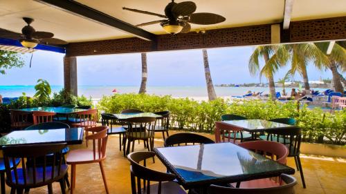 a restaurant with tables and chairs and the beach at Hotel Cocoplum Beach in San Andrés