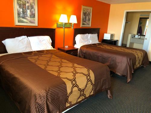 2 camas en una habitación de hotel con paredes de color naranja en Poteau Inn, en Poteau