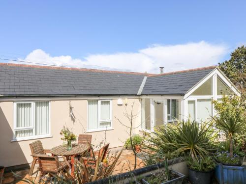 a white house with a table and chairs at Mynheer Farm Bowji in Redruth