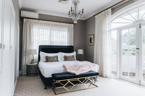 a bedroom with a large bed and a chandelier at Berida Hotel in Bowral