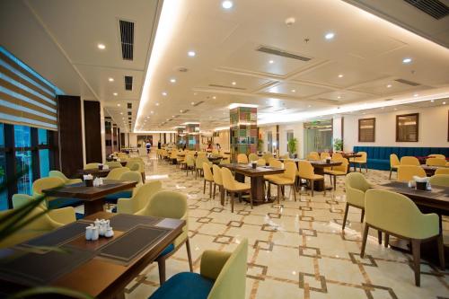 um restaurante com mesas e cadeiras num quarto em Luxury6 Hotel em Móng Cái