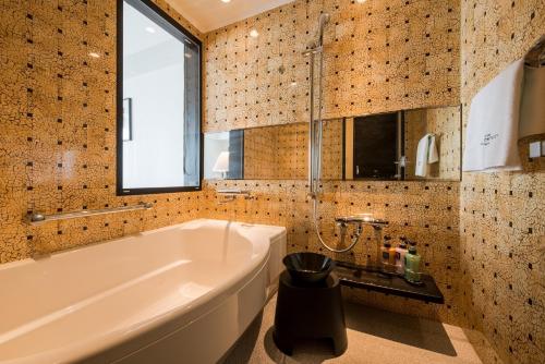 a bathroom with a tub and a window at Hotel Monterey Okinawa Spa & Resort in Onna