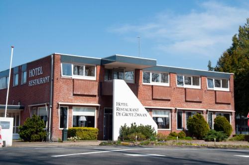 a red brick building with a large sign in front of it at Hotel de Grote Zwaan in De Lutte
