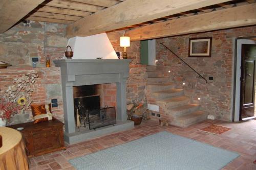 a living room with a stone fireplace and stairs at Torre BALDUCCI in Vicopisano