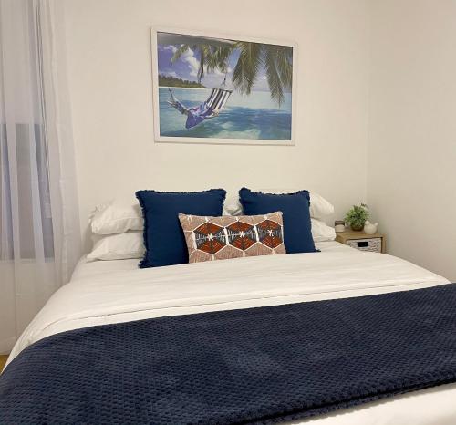 a bedroom with a bed with blue pillows at Kiama Palms on Collins in Kiama
