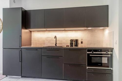 a kitchen with stainless steel appliances and black cabinets at Charmant T2 climatisé - Canebière et Vieux-Port in Marseille