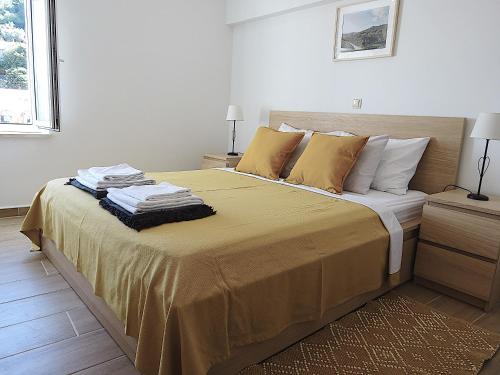 a bedroom with a large bed with yellow sheets and pillows at Eco Apartments Kate in Suđurađ