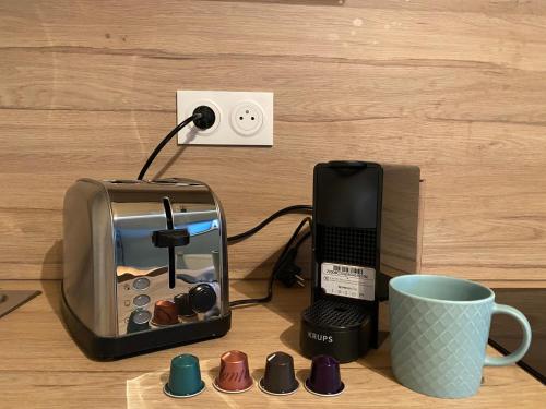 un grille-pain, un téléphone et une tasse sur une table dans l'établissement Capsule Roubaix/Lille Balneo*Home cinéma*Billard, à Roubaix