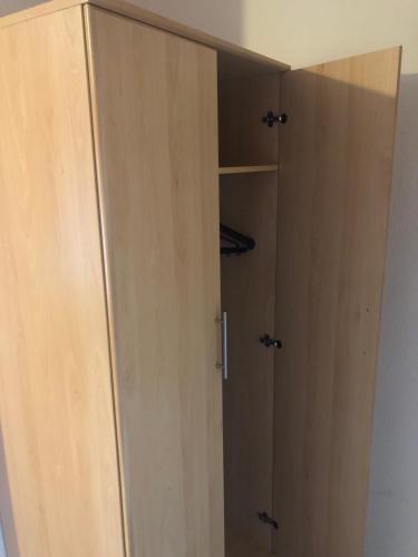 a wooden cabinet with ajar doors in a room at Bright Apartments in Peterborough