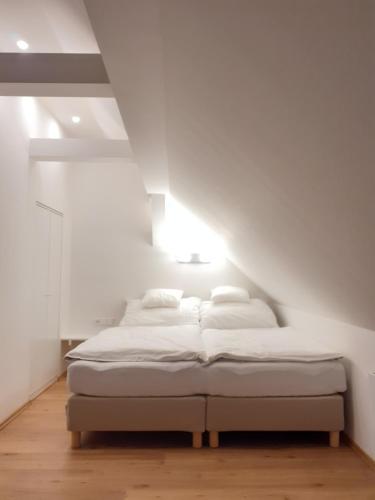 a bed in a room with white walls and wood floors at Apartmány v centru - Lázně Kynžvart in Lázně Kynžvart