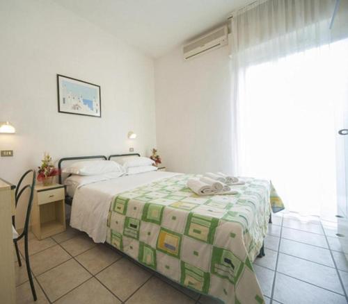 ein Hotelzimmer mit einem Bett, einem Schreibtisch und einem Bett in der Unterkunft Hotel Gemini in Rimini