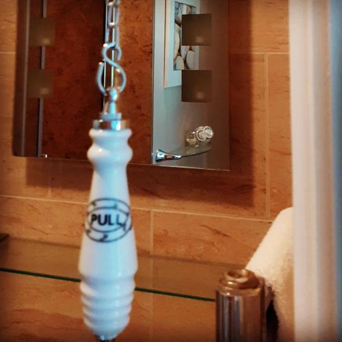 a white bottle hanging from a chain in front of a mirror at The Lychgate in Caldicot
