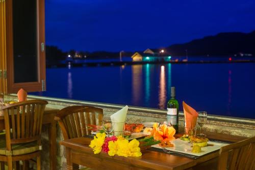 a table with flowers on it with a view of the water at Colibri Hotel in Baie Sainte Anne