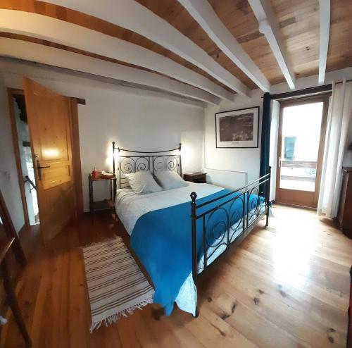 1 dormitorio con 1 cama azul en una habitación con suelo de madera en Les deux arches, en Caunes-Minervois