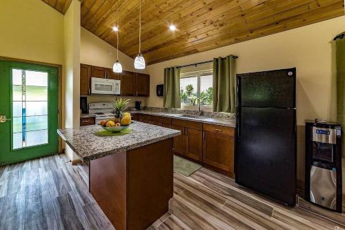 a large kitchen with a black refrigerator and wooden floors at Tropical Island Paradise home in Volcano