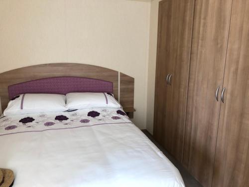 Un dormitorio con una cama y un armario de madera. en Tref y Clawdd, en Felixstowe