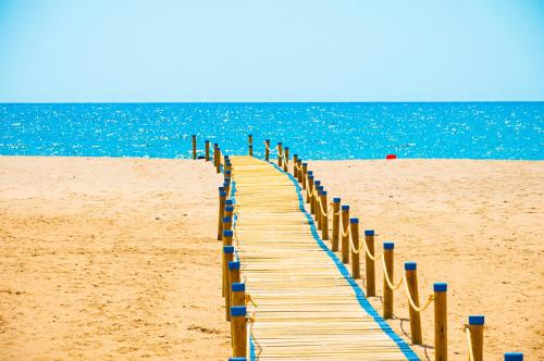 a wooden boardwalk on a beach next to the ocean at Turquesa Beach&Pool Apartaments in Playa Honda