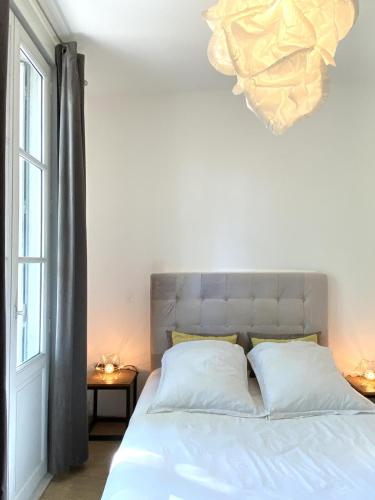 une chambre avec un grand lit blanc avec un lustre dans l'établissement T2 Montpellier centre, climatisé, à Montpellier