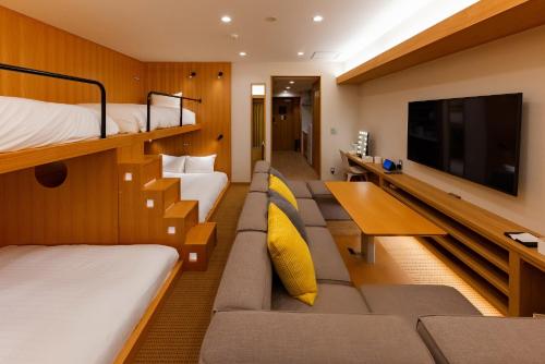 a hotel room with a couch and a tv at GOLD STAY Nagoya Sakae ゴールドステイ名古屋栄 in Nagoya