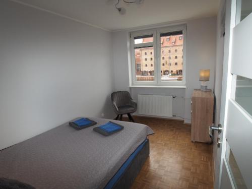 a bedroom with a bed and a chair and a window at Grand-Tourist River Side Apartments in Gdańsk