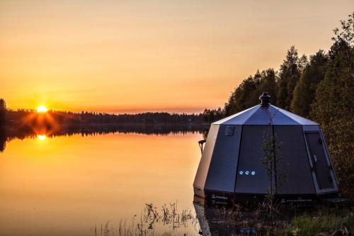 a boat on a lake with the sunset in the background at Laponia Sky Hut in Gällivare
