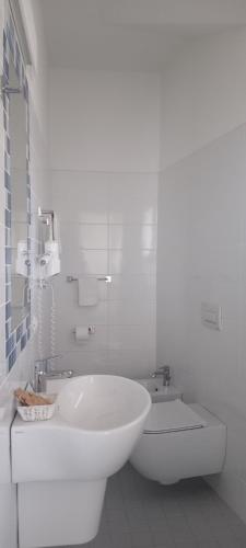 a white bathroom with a tub and a sink at Albergo Medusa in Punta Marina