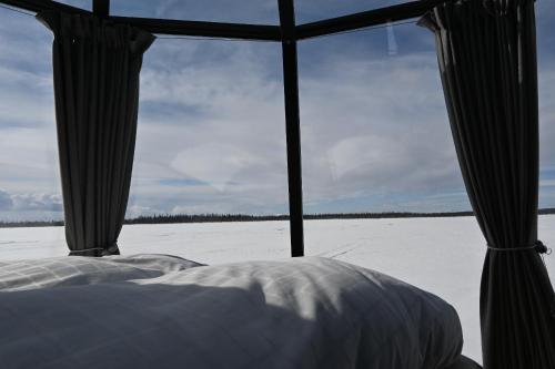 vistas a una cama y a un campo cubierto de nieve en Laponia Sky Hut en Gällivare