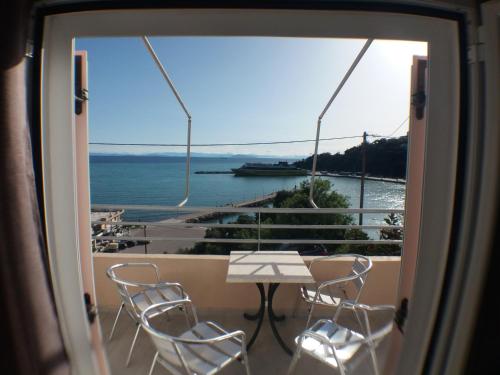 a table and chairs on a balcony with a view of the water at Harbour View - Oceanis Apartments in Poros