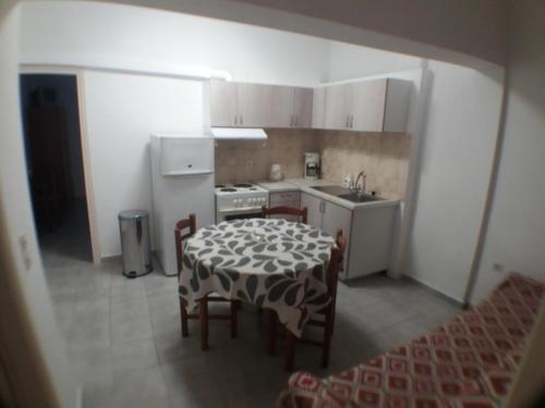 a kitchen with a table and chairs and a white refrigerator at Harbour View - Oceanis Apartments in Poros
